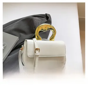 Macro shot of stylish white patent leather bag with a unique gold organic shaped handle
