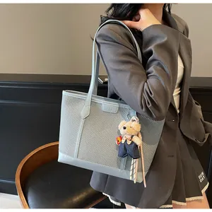 Close-up of light blue woven tote bag with a cute plush bear charm for daily commuting