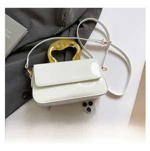 White glossy envelope bag featuring unique fluid gold metal handle and slim shoulder strap