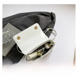 Interior view showing the capacity of a white glossy leather crossbody bag with items