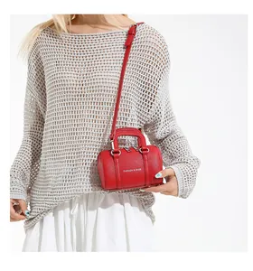 Detail of red lychee textured Boston bag with silver lettering and adjustable strap