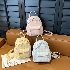 Three macaron-toned gingham mini backpacks in pink, yellow, and blue arranged on a sofa
