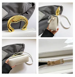 Detail view of white leather handbag featuring a unique gold metal handle and hardware