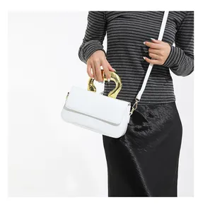 Detailed shot of white faux leather envelope bag featuring a gold sculptural metal handle