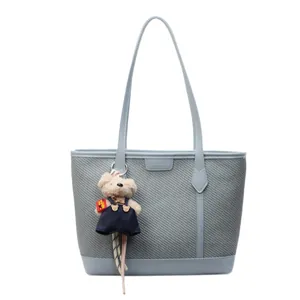 Blue-grey woven tote bag with leather trim and cute teddy bear charm for daily commute