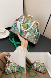 Detail der Blumenstickerei auf grüner Muscheltasche mit Perlengriff und Metallverschluss