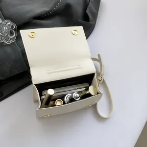Detailweergave van de binnenruimte van de ivoren PU-lederen tas met telefoon en lippenstiften