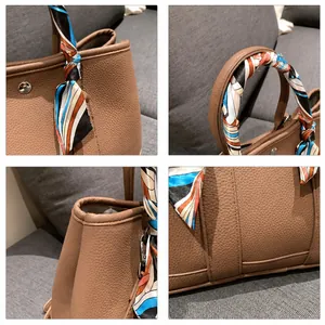 Détail du sac à main en cuir marron avec foulard en soie imprimé et ferrures en métal argenté