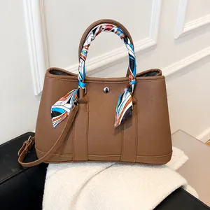 Détail d'un sac cabas en cuir marron foncé avec foulard en soie sur la poignée