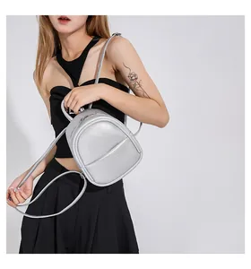Detail of a silver mini egg-shaped backpack with metallic texture on a model