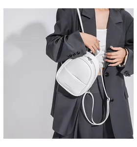 Detail of white lychee leather mini backpack with Fashion & Bags text on grey blazer