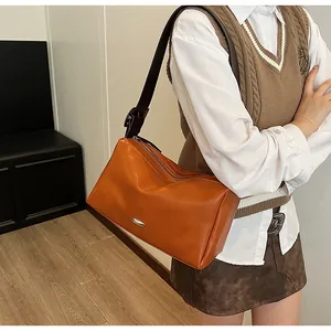 Detail of caramel faux leather shoulder bag with wide strap and oval silver buckle