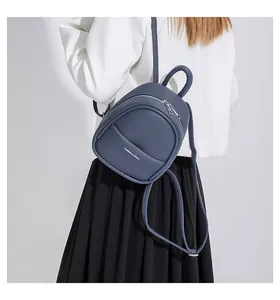 Detail of navy blue pebble leather mini backpack showing the curved zipper pocket and logo
