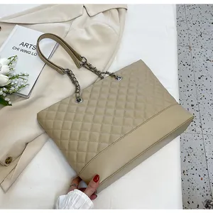 Detail view of beige quilted tote bag with silver chain strap and leather stitching