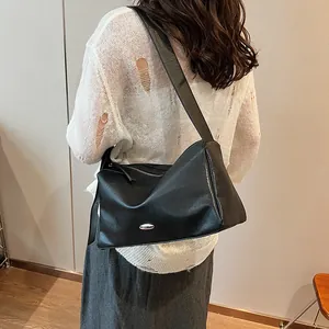 Retro black minimalist crossbody bag with silver oval hardware shown on model