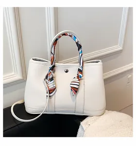 Détail du sac à main en cuir blanc avec foulard en soie et fermoir métallique