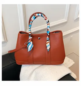 Détail d'un sac cabas en cuir caramel avec foulard en soie et bouton pression en argent