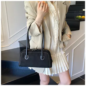 Detailed view of black matte leather baguette bag with white contrast stitching and zippers