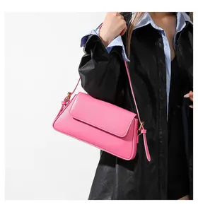 Detail of pink leather shoulder bag with gold hardware worn by a model in casual outfit