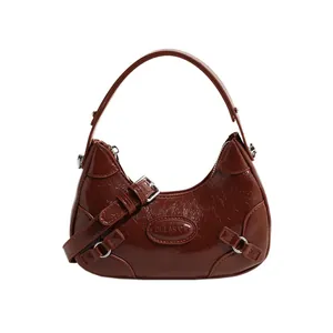 Caramel brown crescent shoulder bag in glossy leather with adjustable silver buckle