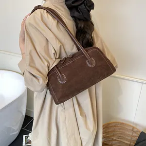 Brown suede baguette bag with contrast white stitching and dual zippers on shoulder strap