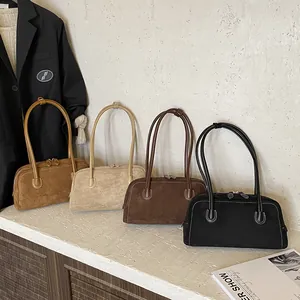 Minimalist suede baguette bags in earth tones with dual straps on white display stand
