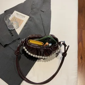 Dark brown pleated cloud crossbody bag with pearl handle and leather strap showing interior capacity