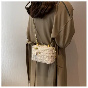 Dettaglio borsa a tracolla in tweed con logo camelia dorata su un trench coat