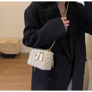Détail d'un sac bandoulière en tweed avec chaîne et double fermeture éclair sur modèle