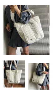 Dettaglio della borsa tote plissettata bianco crema con trama del tessuto e logo in metallo