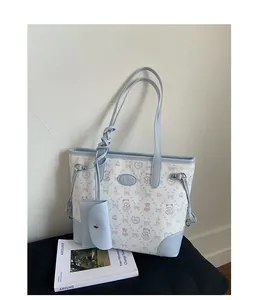 Detail of blue and beige bucket bag with cartoon bear prints and small coin purse charm