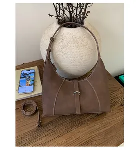 Detail view of brown suede hobo bag featuring white contrast stitching and dual straps