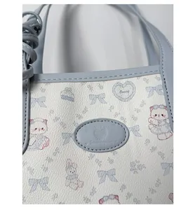 Close-up of light blue leather bucket bag with cute cat prints and embossed logo