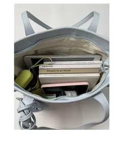 Top view of spacious interior of blue leather bucket bag with gadgets and books