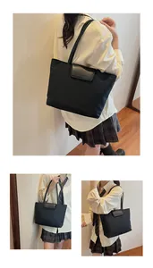 Dettaglio della borsa tote in nylon nero con patta in pelle e logo inciso per il lavoro