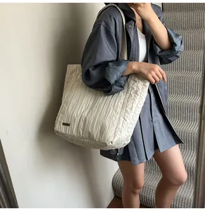 Grande borsa tote a pieghe color bianco sporco alla moda indossata da una modella