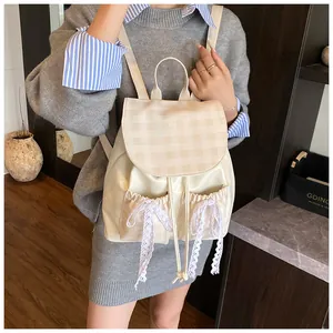 Close-up of cream backpack featuring plaid flap and lace bowknot decoration