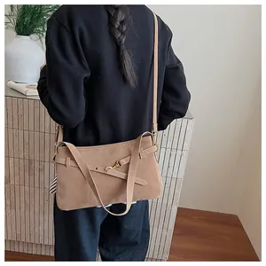 Rear view of a model wearing the brown frosted suede shoulder bag with gold hardware