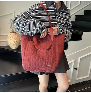 Dettaglio ravvicinato della borsa tote trapuntata bordeaux con texture a onde e fibbia