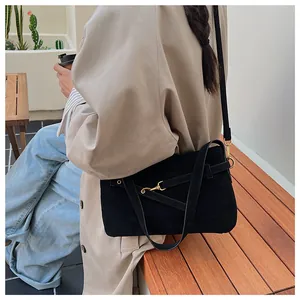 Detail of black matte leather crossbody bag with gold buckle on a beige trench coat