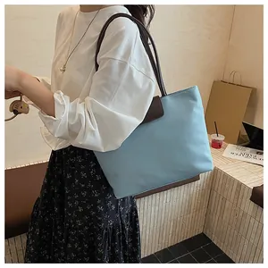 Dettaglio della borsa tote in nylon celeste con manici in pelle marrone indossata