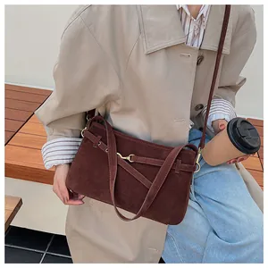 Close-up of vintage brown suede shoulder bag with gold metal buckle and strap details