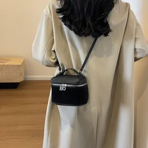 Schwarze Mini-Handtasche aus Leder mit Silber-Details zu einem beigen Mantel