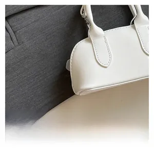 Detail of white glossy shell bag showing high-shine patent texture and refined stitching