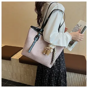 Pink embossed tote bag with black leather strap and bear charm accessory details