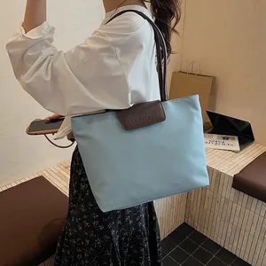 Borsa tote celeste con manici in pelle marrone, mostrata indossata a spalla