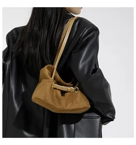 Dettaglio borsa sottobraccio in pelle scamosciata marrone con tracolla in pelle e fibbie