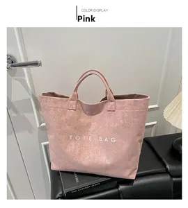 Dettaglio borsa tote in finta pelle scamosciata rosa con scritta bianca su panca in pelle