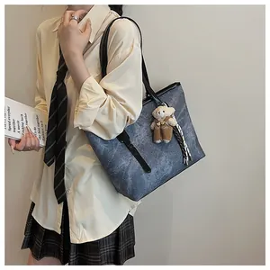 Detail view of vintage embossed tote bag with teddy bear charm shown on model's shoulder