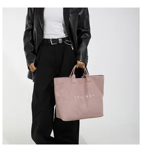 Borsa tote in velluto rosa con scritta TOTE BAG indossata da modella in pelle nera